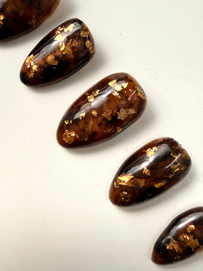 5 press on nails designed in tortoise shell with gold flakes closer up