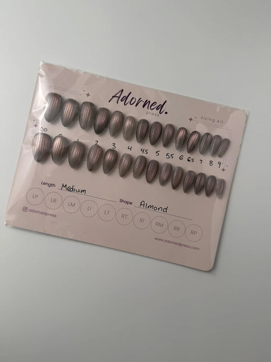 Set of light grey cateye press on nails in packaging on a light cream background