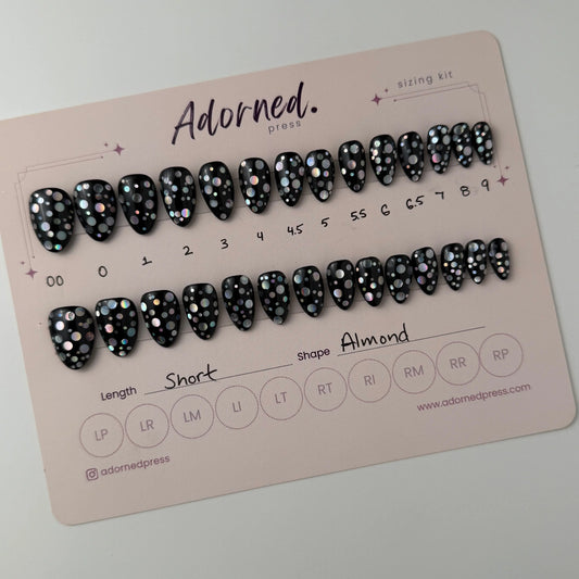 Set of false nails on a display card with brand name 'Adorned' on a light background